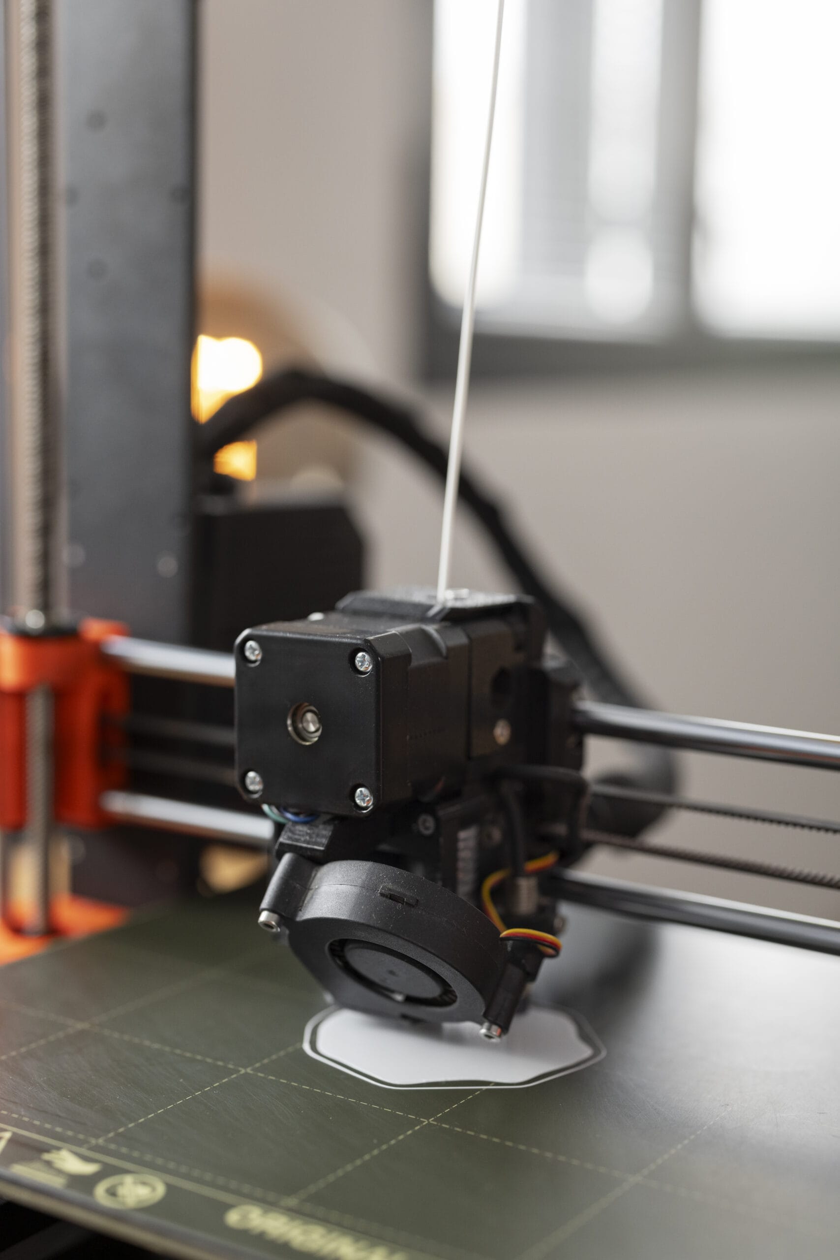 Close-up of 3D printer nozzle extruding filament onto print bed.